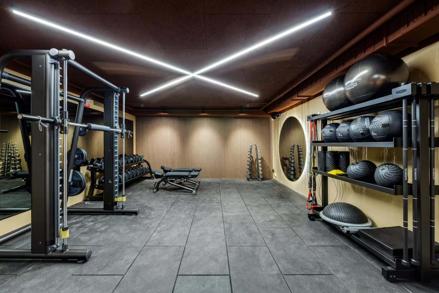 Ett modernt gym med träningsutrustning, fria vikter och belysning i taket.