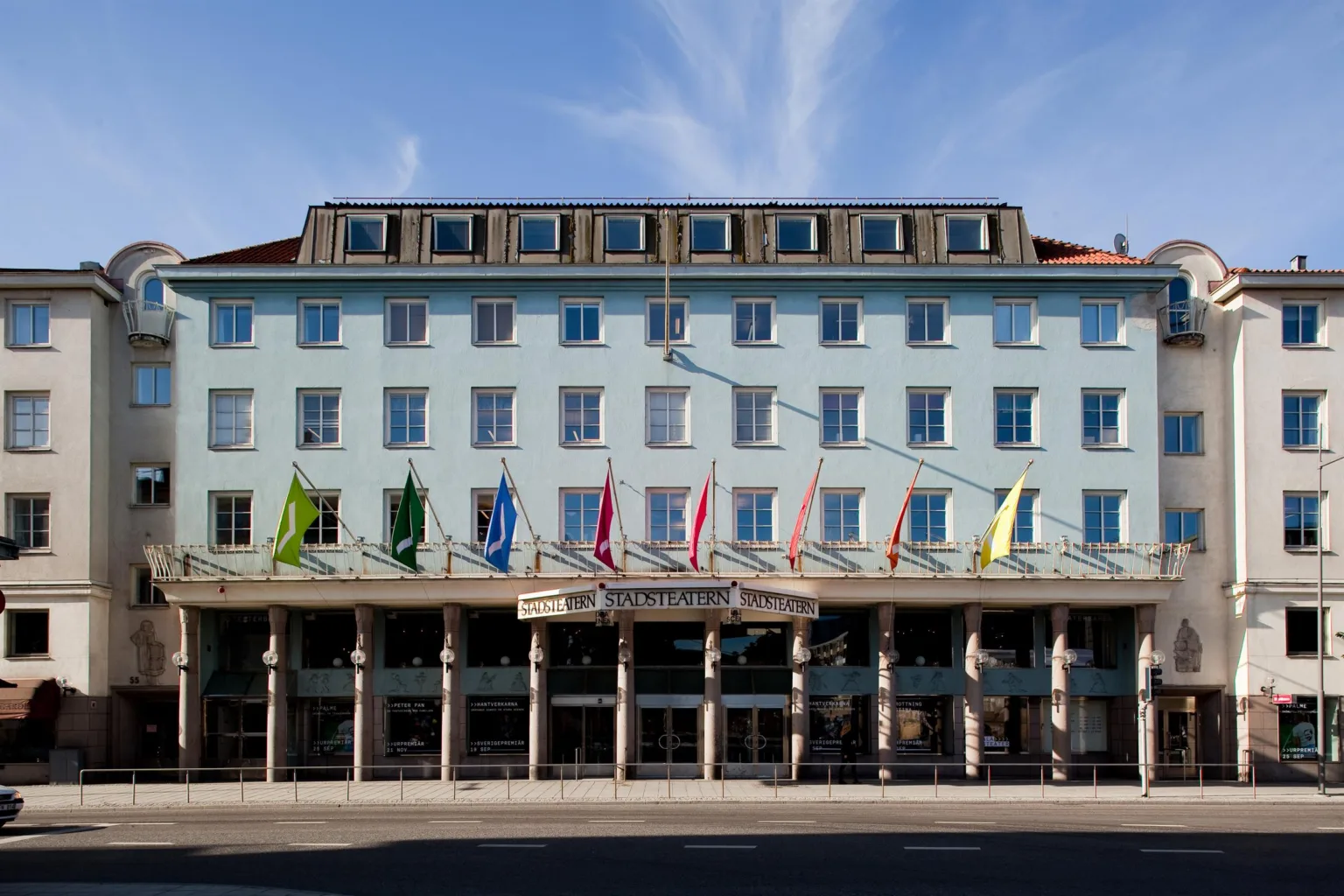 2. En ljusblå byggnad med flera flaggor på fasaden, klar himmel i bakgrunden.