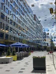 En gågata med blå parasoller, uteserveringar och dekorationer som hänger ovanför.