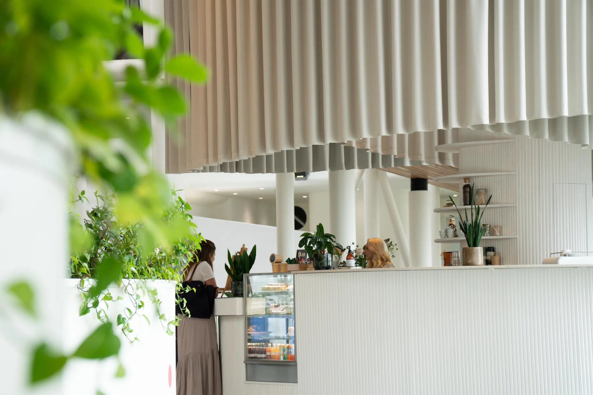 5. En modern inomhusmiljö med en vit disk, hängande dekorativa paneler och gröna växter i förgrunden.