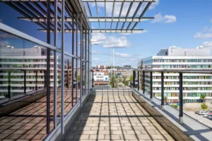 En takterrass med glastak och utsikt över moderna byggnader.