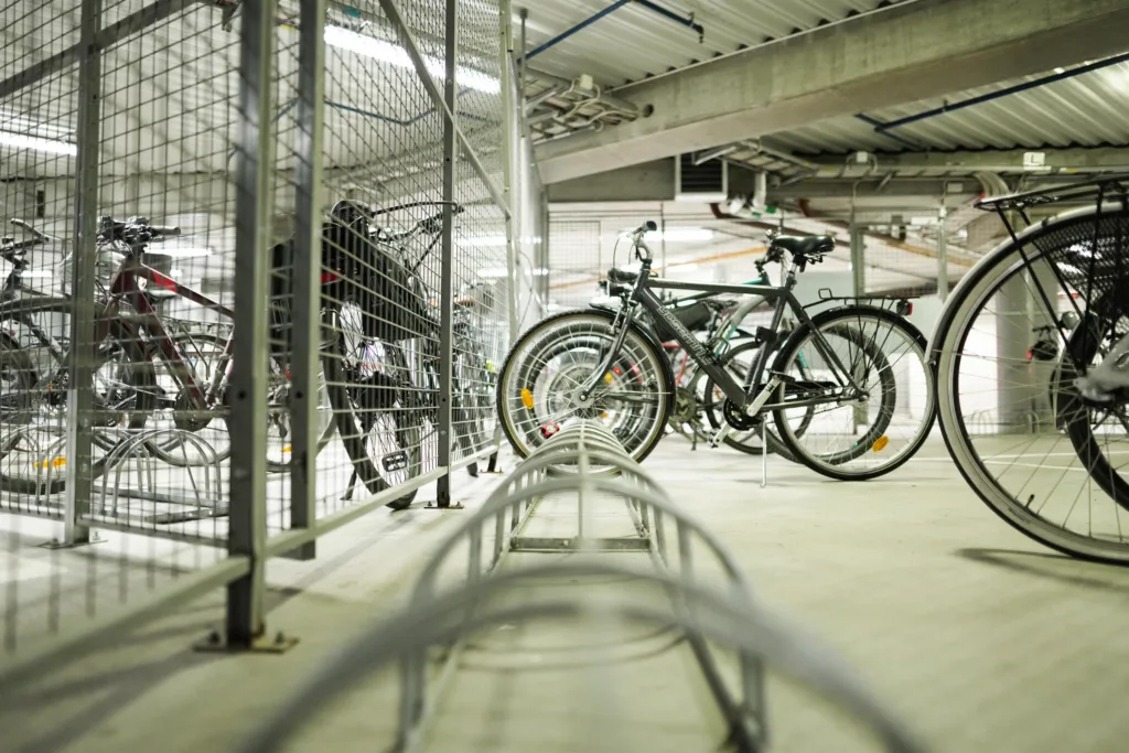 En cykelparkering inomhus med flera cyklar och ett metallstaket.