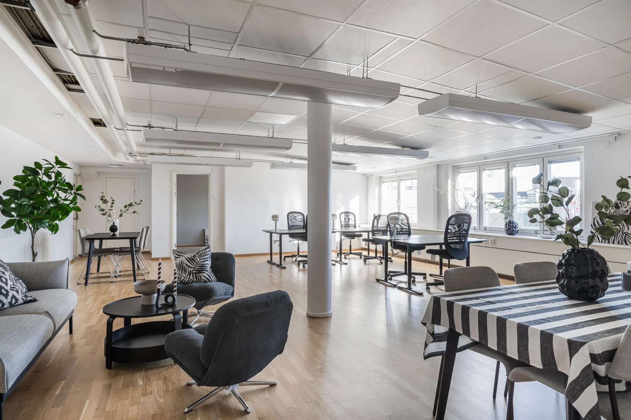 5. Ett stort kontorsutrymme med skrivbord, stolar och en sittgrupp med soffor och bord.