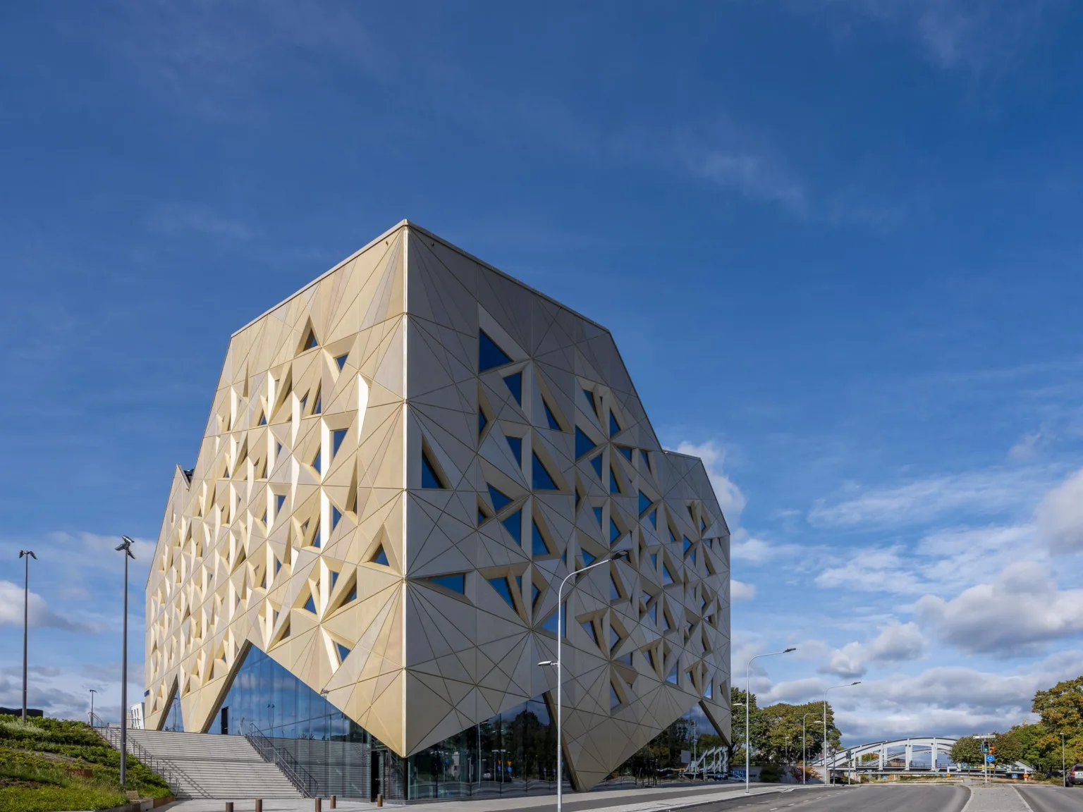 En modern byggnad med triangulära fönster och geometriska former mot en klarblå himmel.