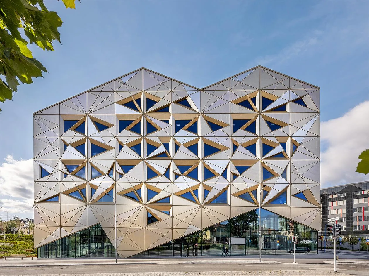 1. En modern byggnad med geometriska triangulära fönster och fasaddesign under en klarblå himmel.