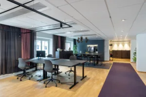 En öppen kontorsmiljö med skrivbord, stolar, och en blandning av moderna och klassiska inredningsdetaljer.