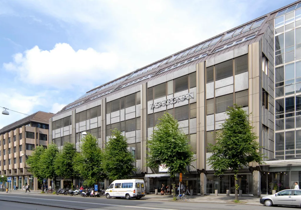 3. En byggnad med glasfasad och träd längs gatan, en vit skåpbil är parkerad framför.