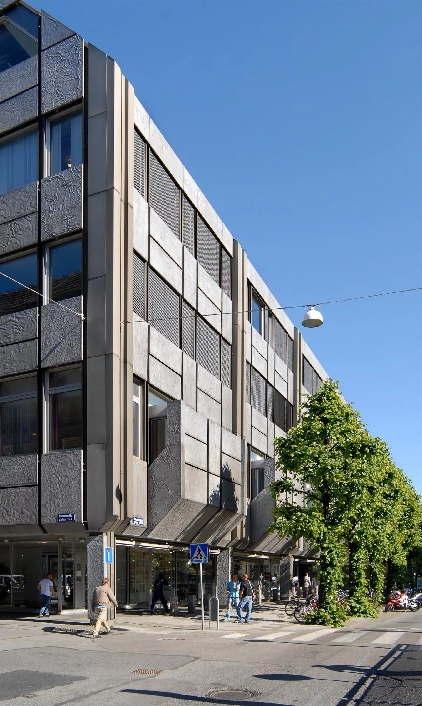 1. En modern byggnad med glas- och betongfasad under en klarblå himmel, omgiven av grönska.