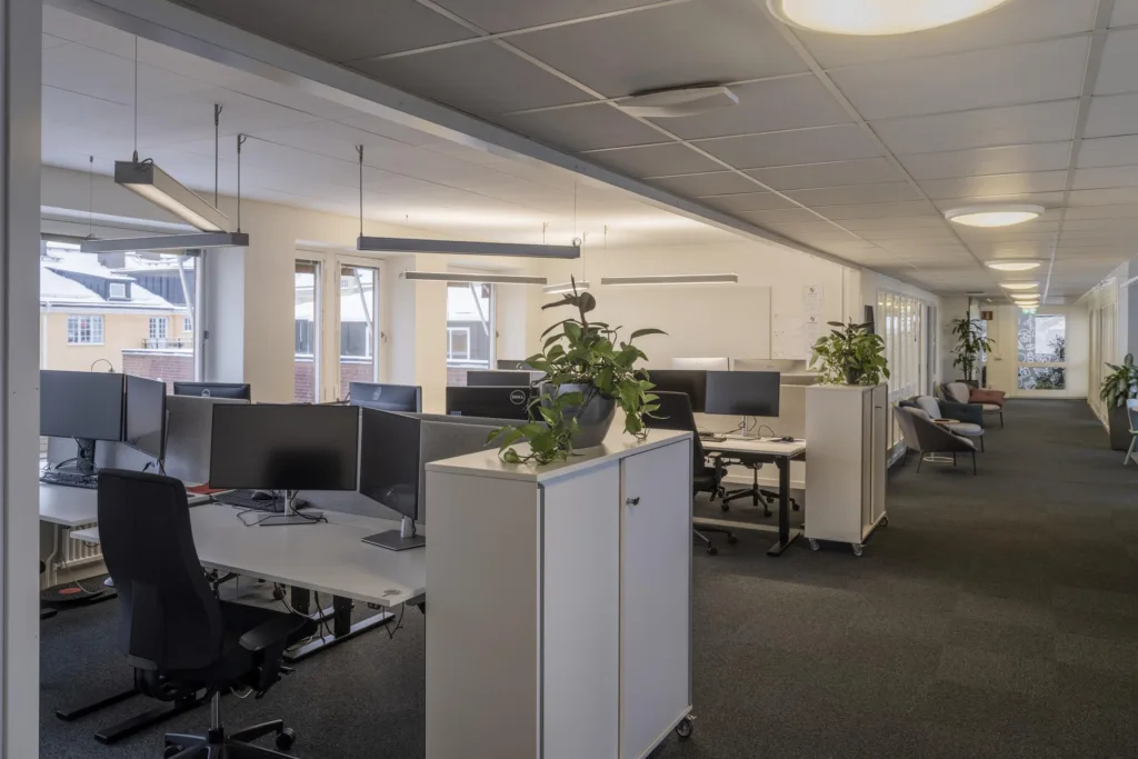 2. Ett öppet kontorslandskap med arbetsstationer, skåp och växter.