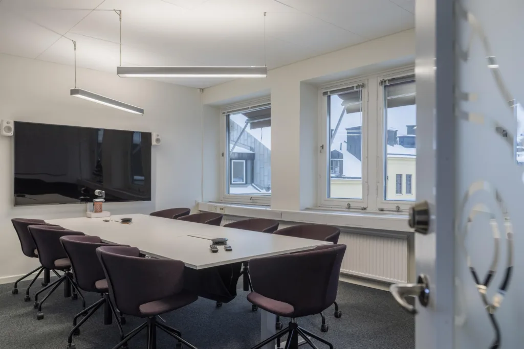 4. Ett mötesrum med ett långt konferensbord, stolar och stora fönster.
