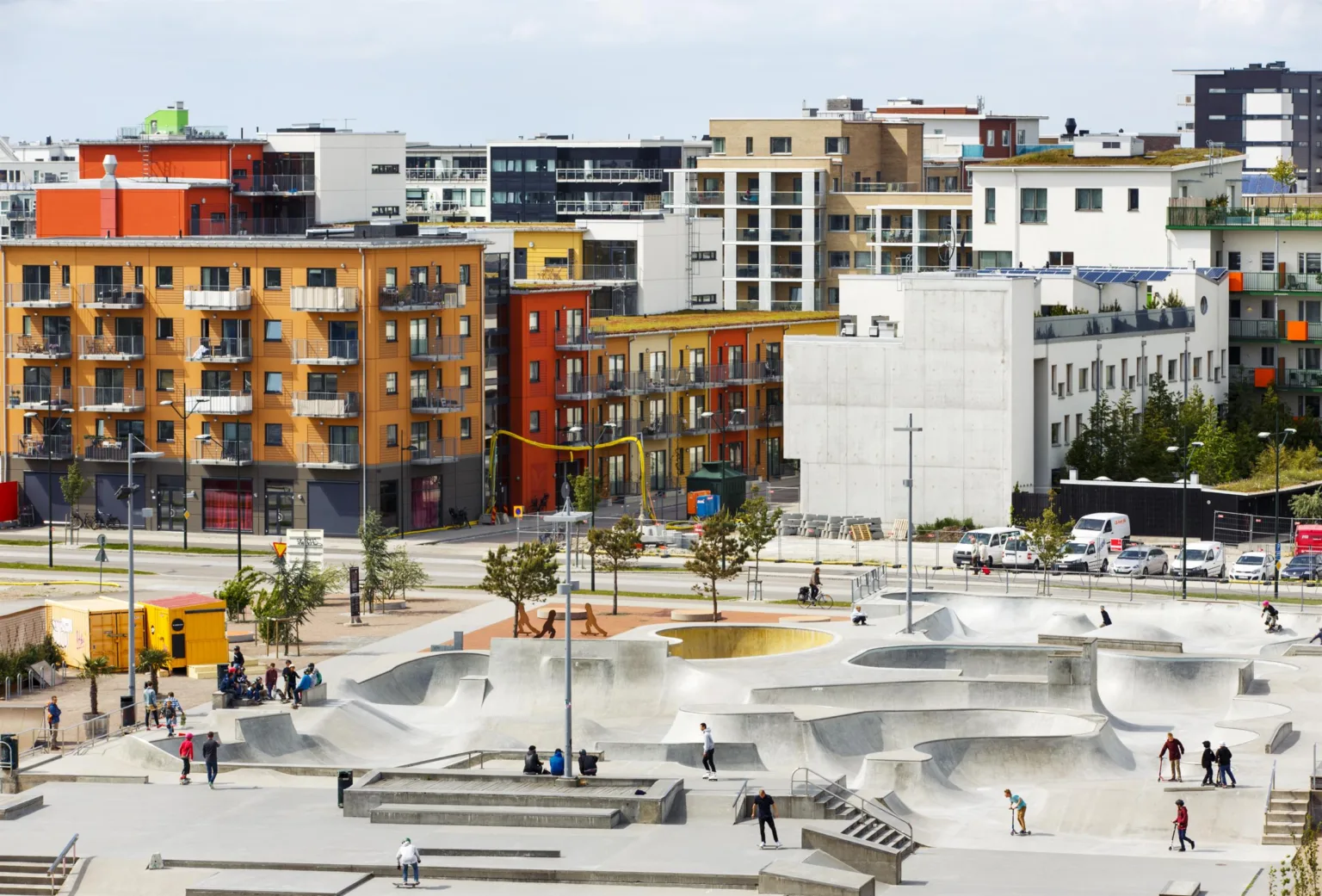 2. En skatepark med flera ramper omgiven av färgglada byggnader och träd.