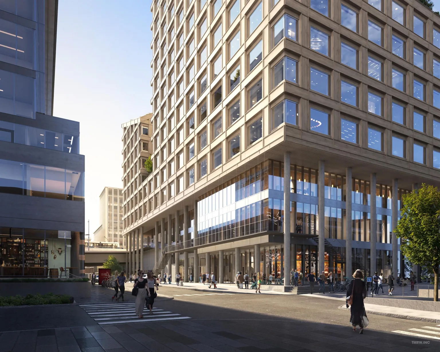 En modern byggnad med glasfasad och flera våningar, omgiven av fotgängare och andra byggnader.
