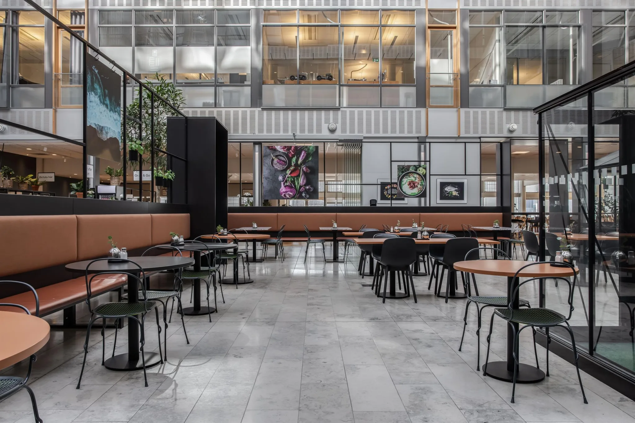 En modern matsal med flera bord och stolar, marmorgolv och glasväggar.
