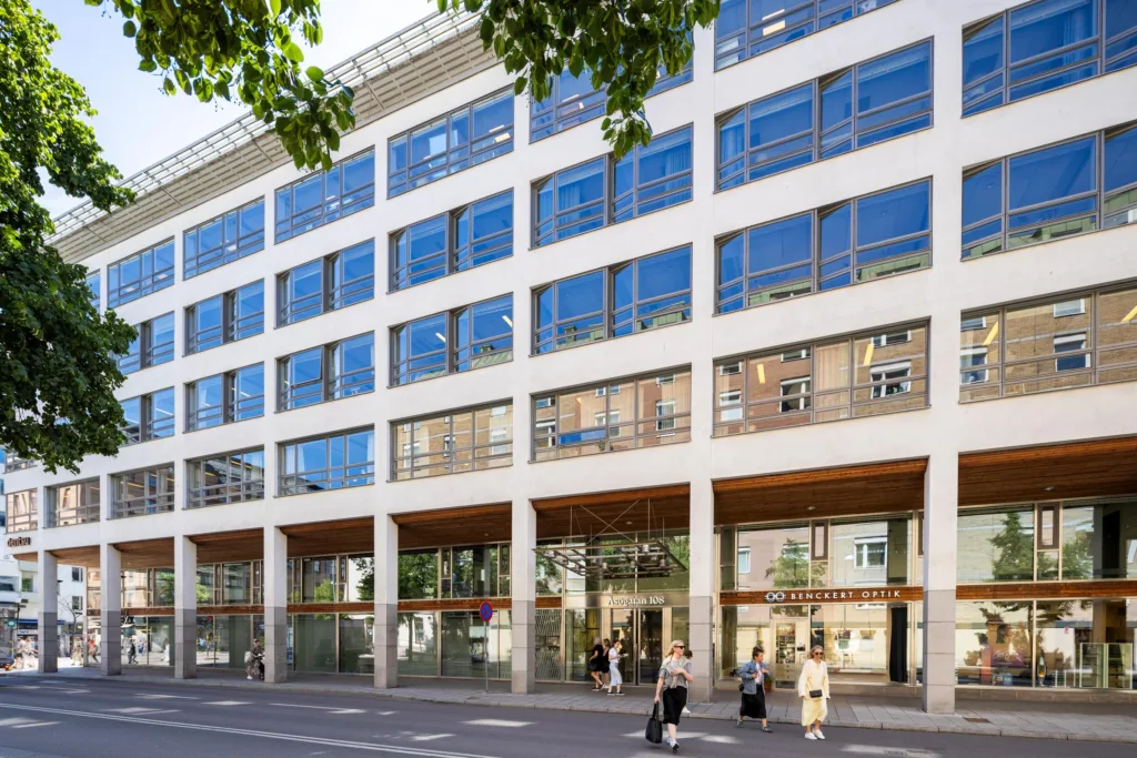 En modern byggnad med stora glasfönster och människor som går på trottoaren.