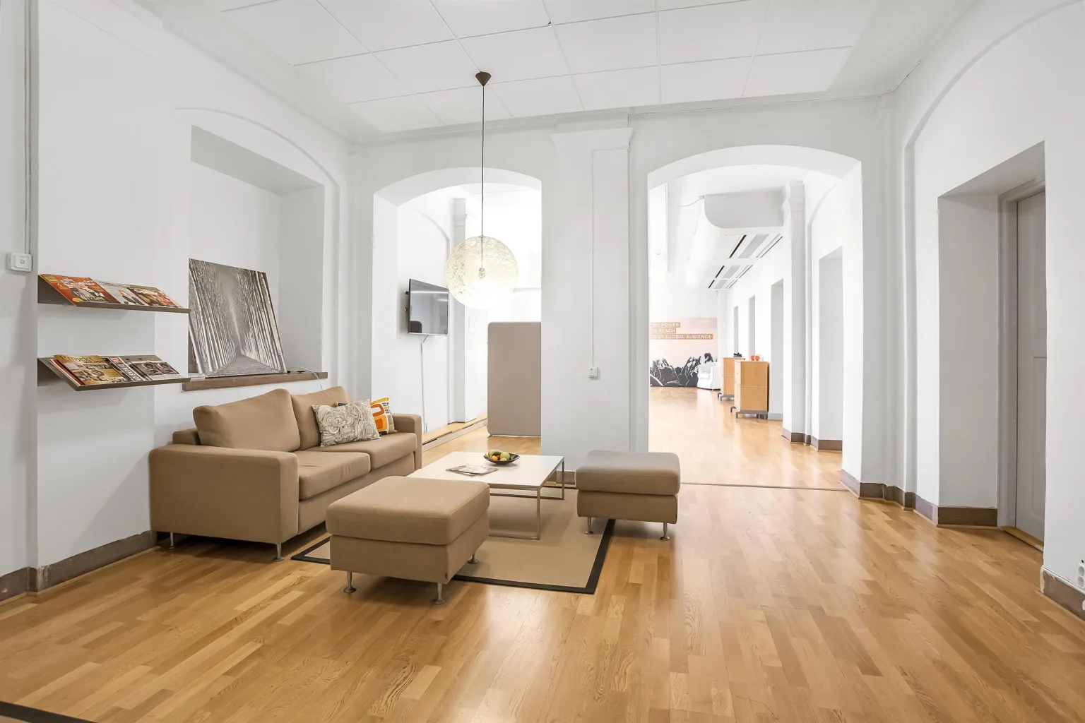 Ett ljust vardagsrum med beige soffa, soffbord och trägolv.