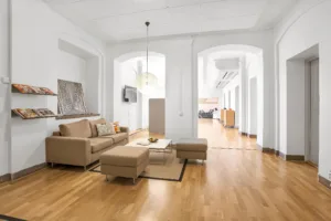 Ett ljust vardagsrum med beige soffa, soffbord och trägolv.