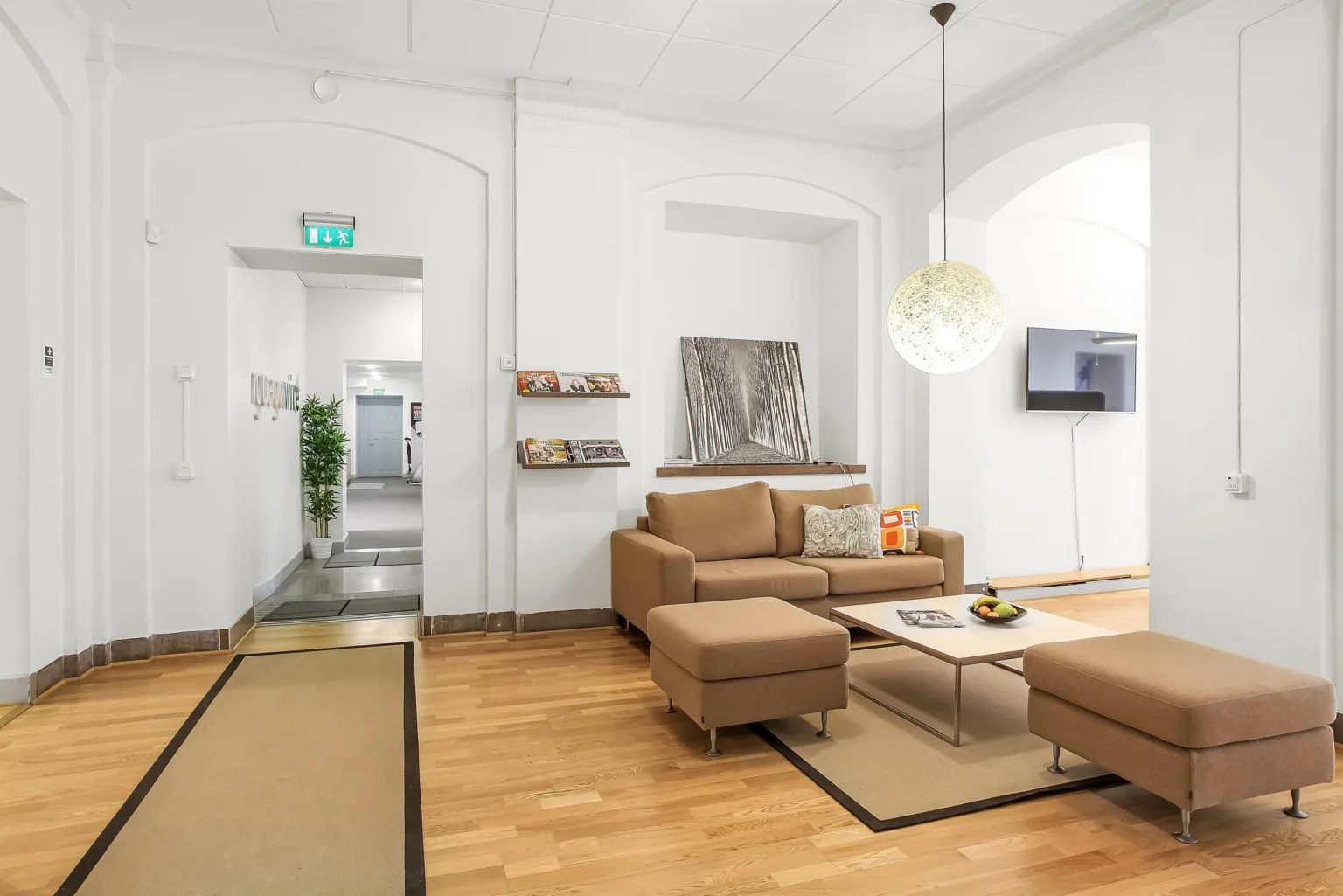Ett vardagsrum med beige möbler, väggdekorationer och en hängande lampa.