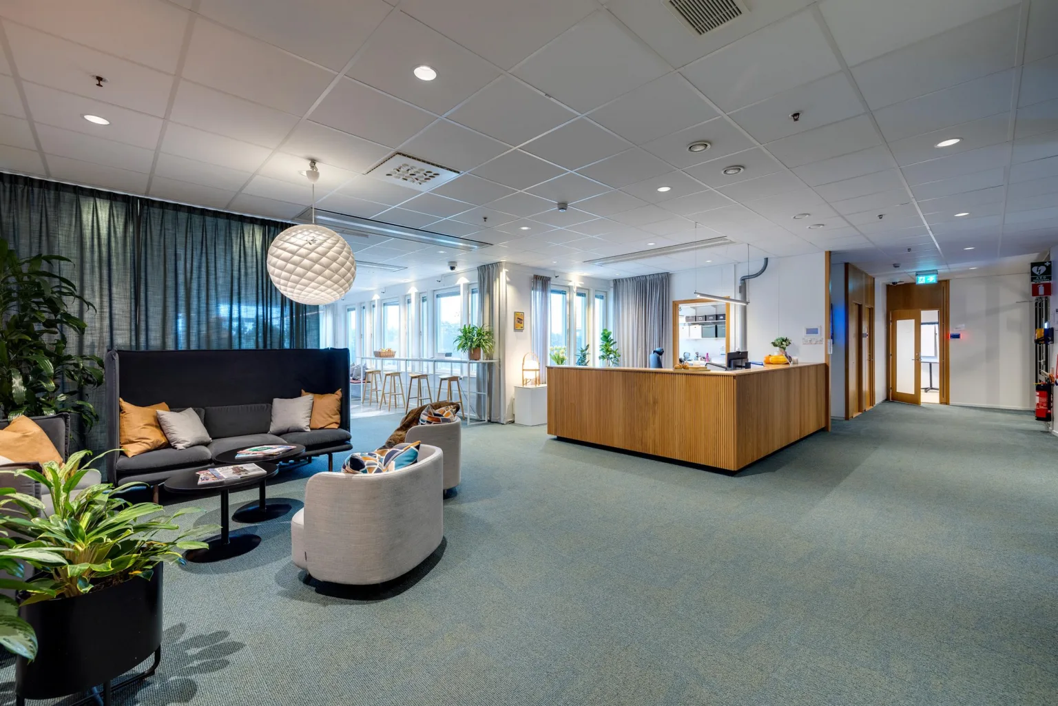 5. En reception med en trädisk, sittgrupp med soffor och bord, samt dekorativa element som en stor lampa och växter.