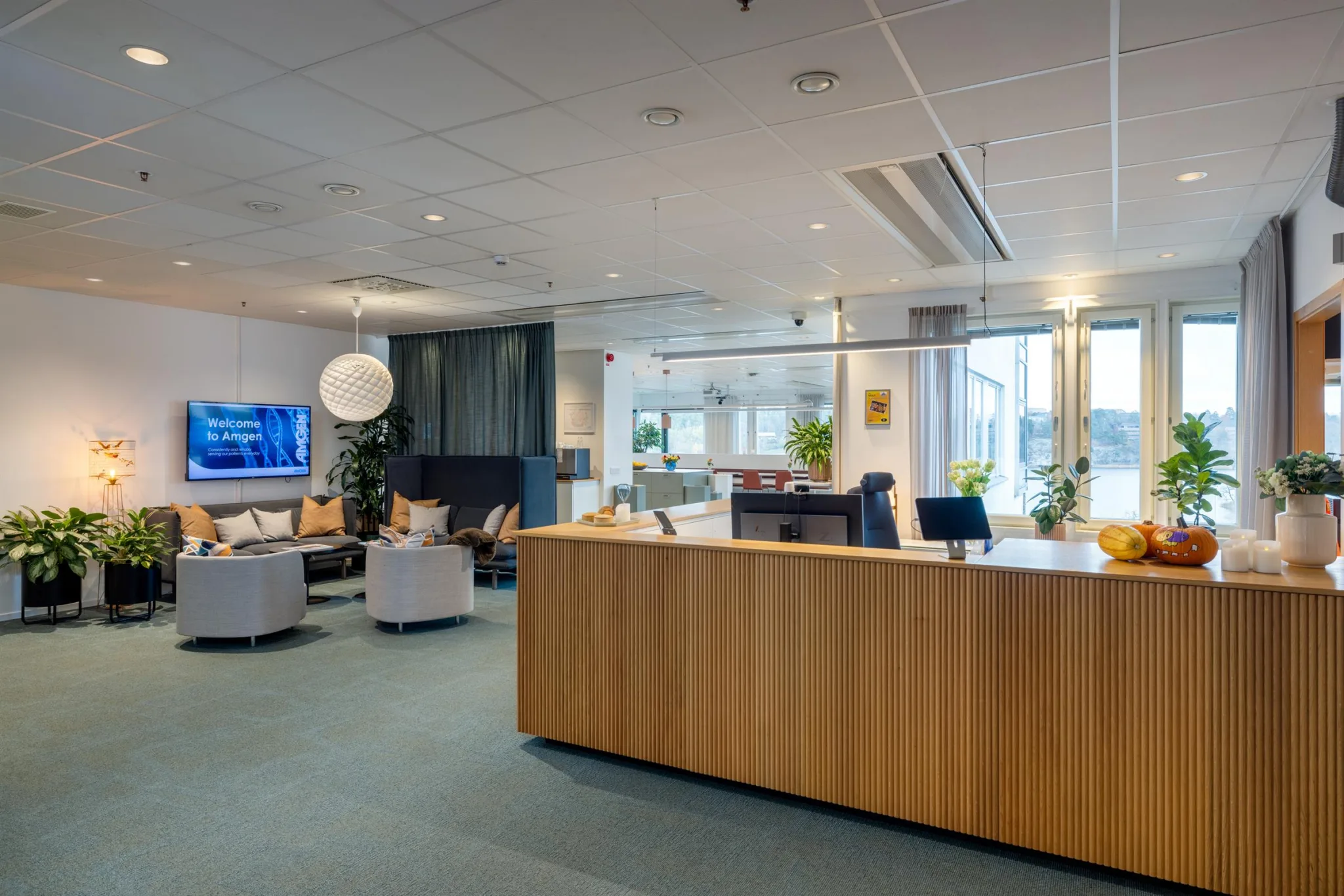 2. En reception med en trädisk, sittgrupper och växter i en ljus och modern miljö.