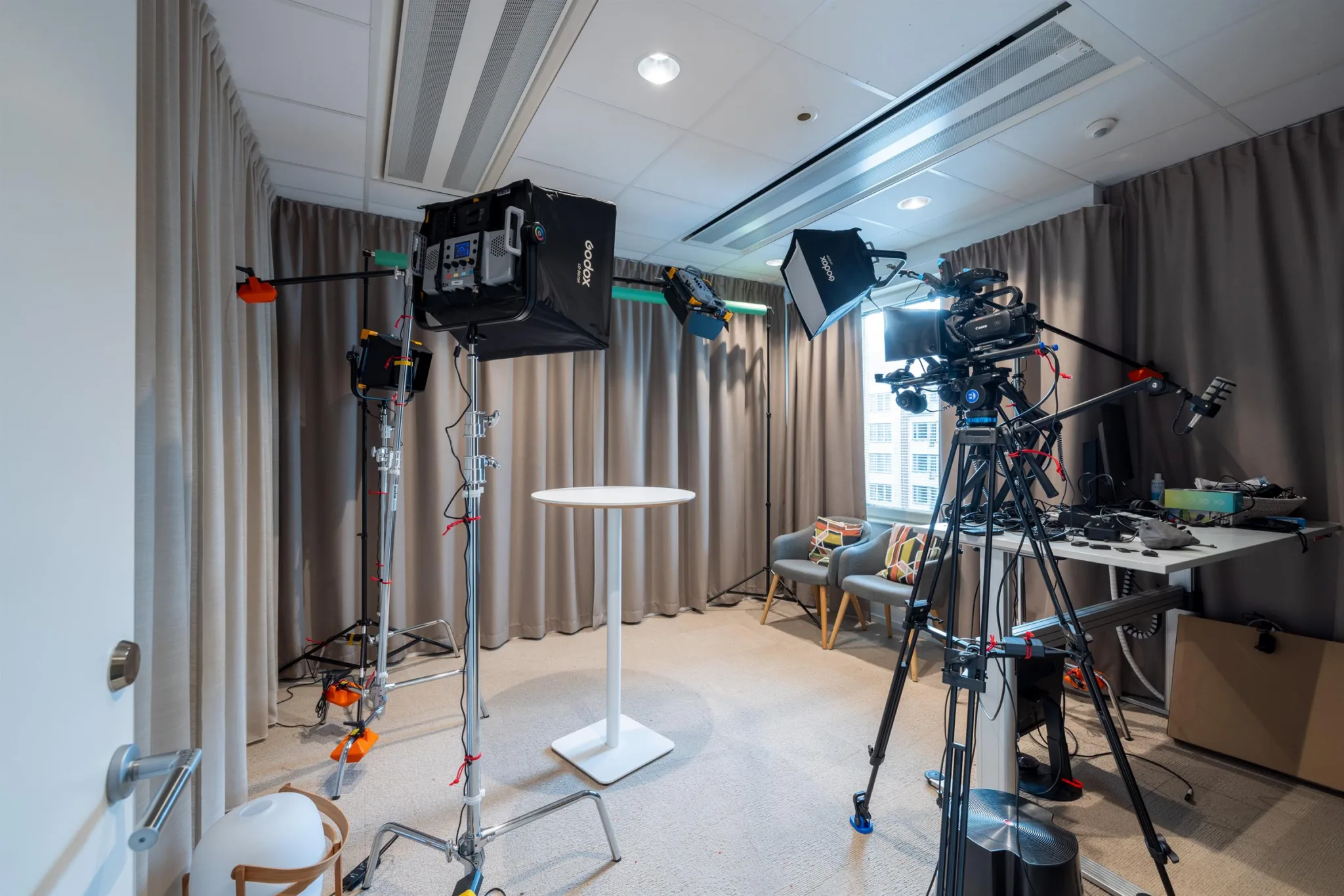 Ett rum med kameror, belysning och ett vitt bord, utrustat som en film- eller fotostudio.