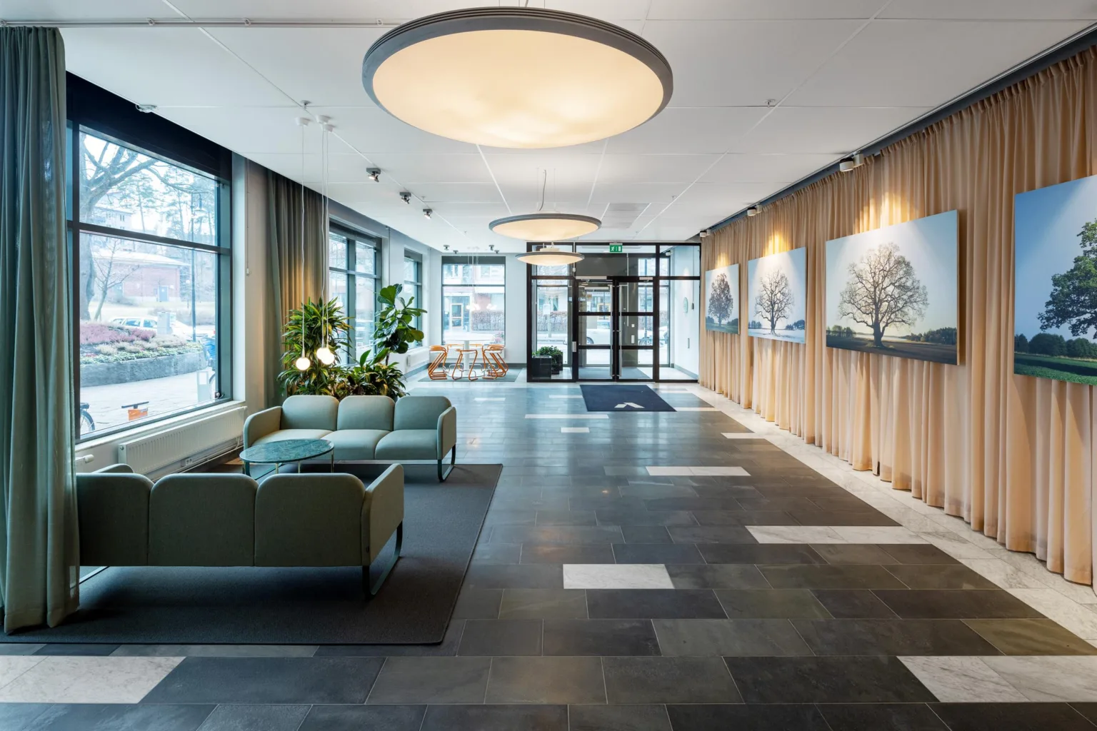 3. En elegant lobby med soffgrupp, stora taklampor och konstverk på väggarna.