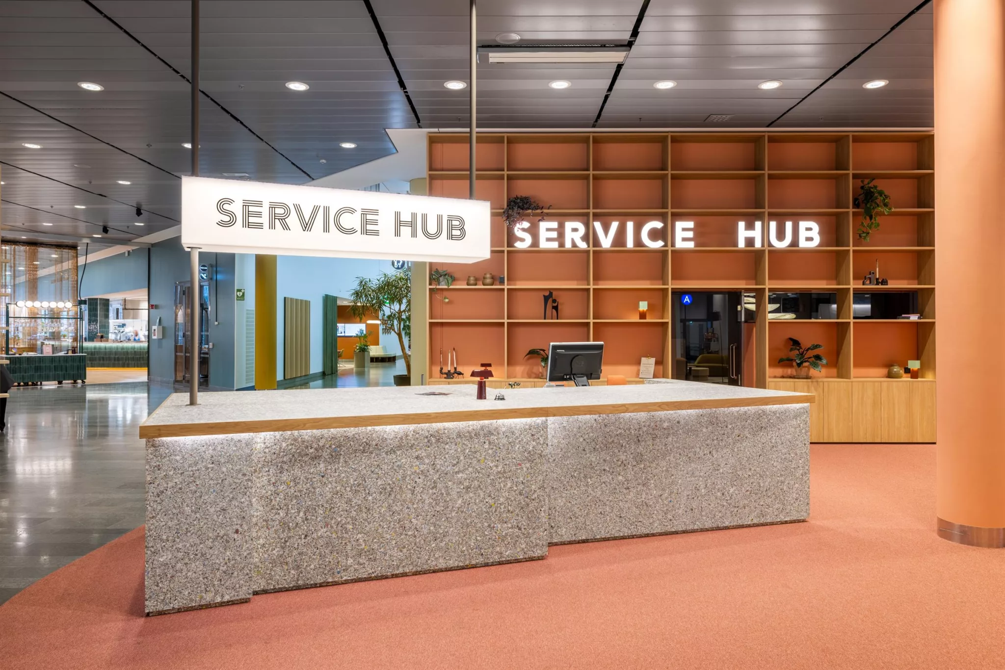 3. En reception med en skylt som lyder "SERVICE HUB", med en ljus disk och hyllor i bakgrunden.