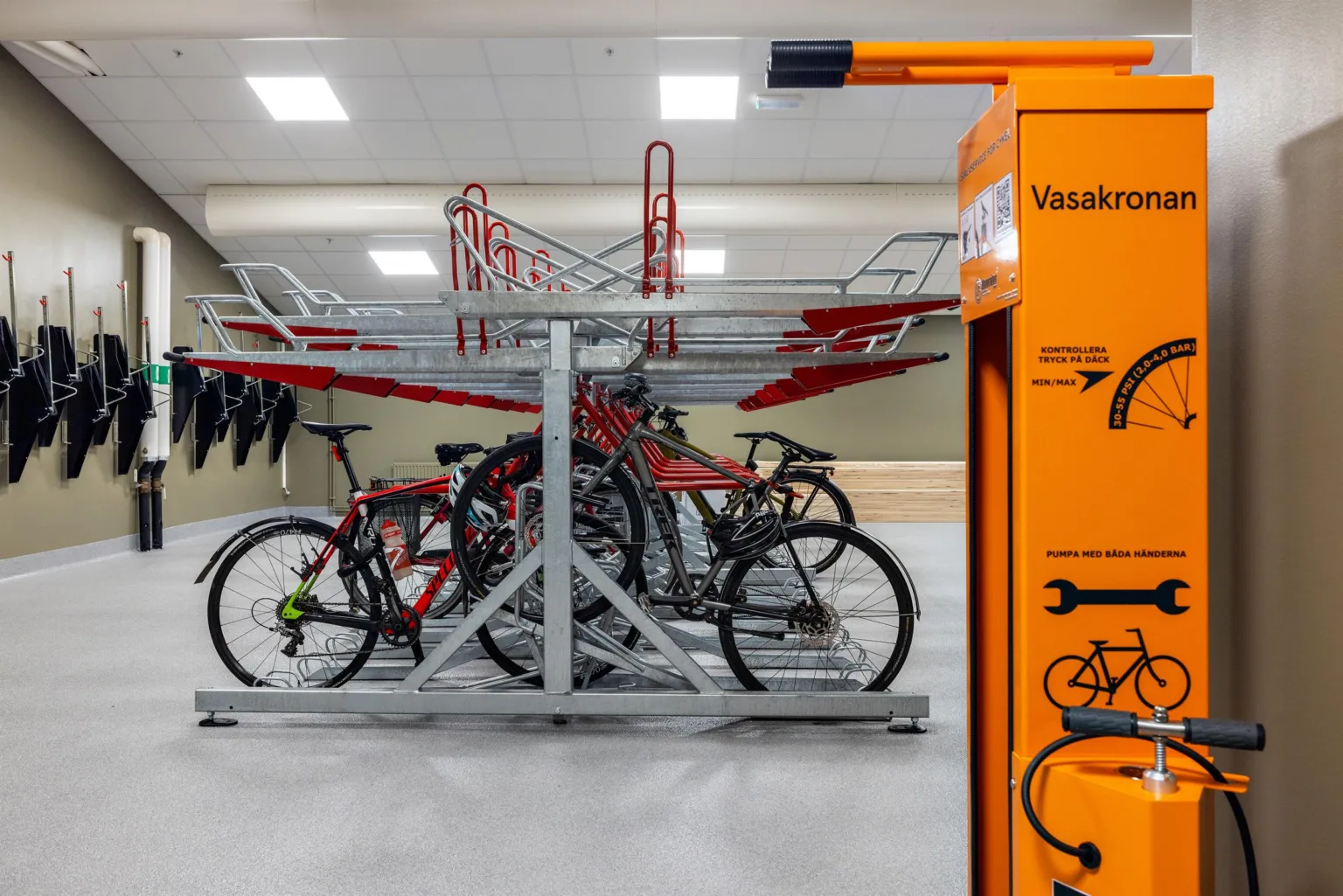En cykelparkering med flera röda cyklar och en orange station för cykelservice.