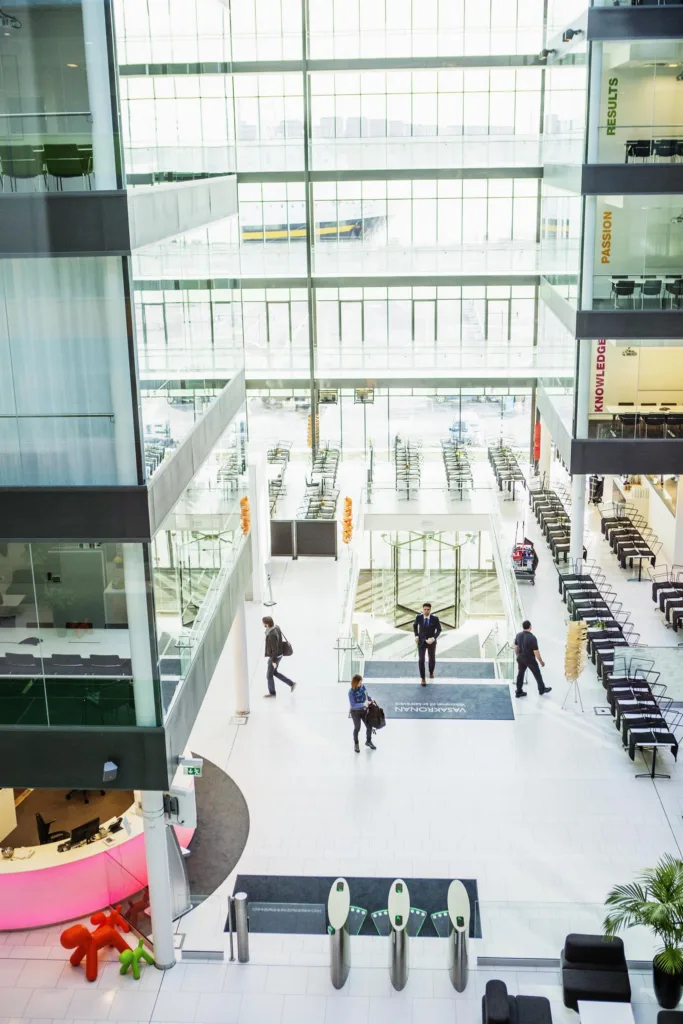 5. Ett stort, öppet atrium med glasväggar, sittplatser och människor som rör sig genom utrymmet.