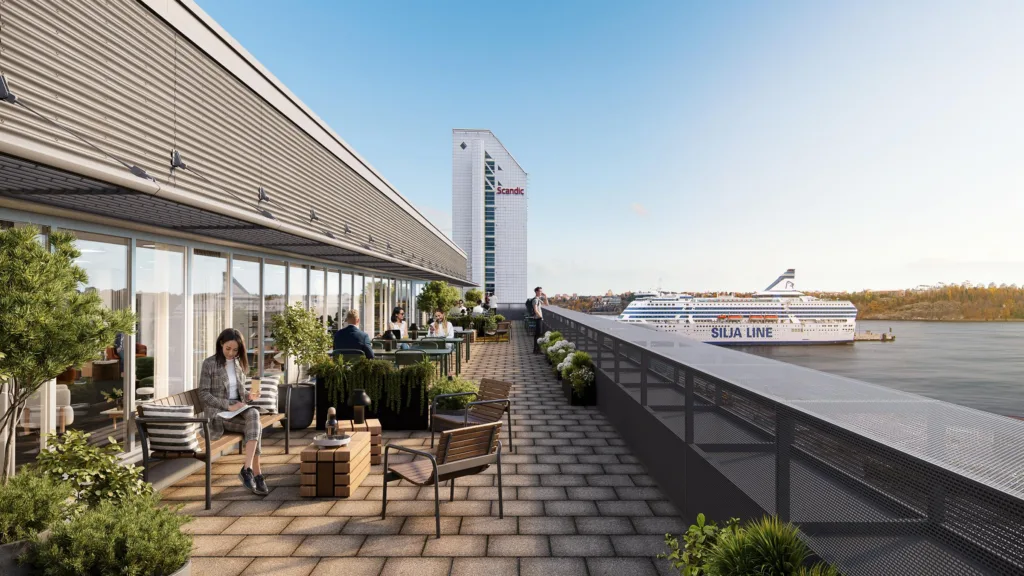 3. En takterrass med sittmöbler, växter och utsikt över en hamn och ett höghus i bakgrunden.