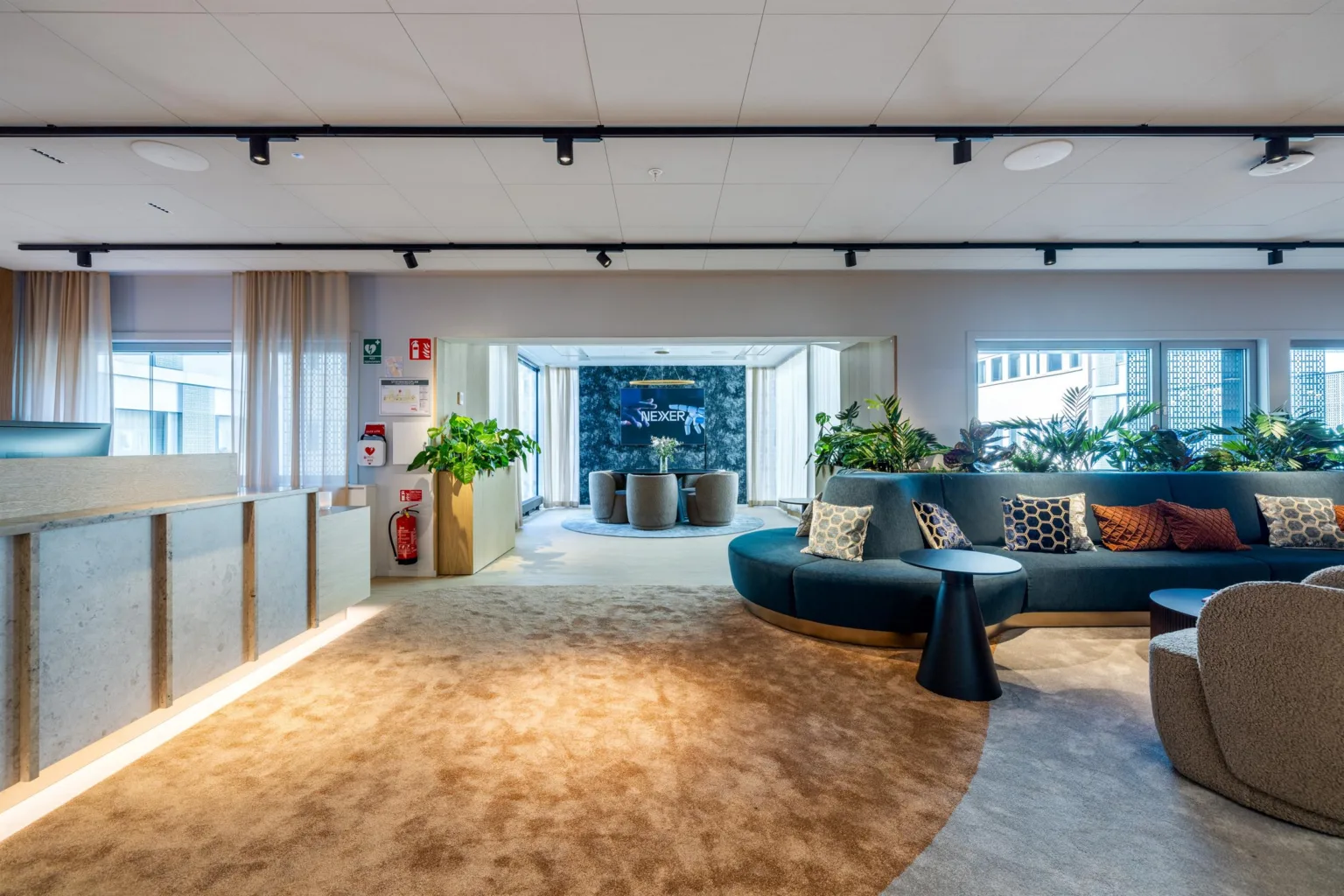 1. En modern lounge med en rund soffa, gröna växter och stora fönster som släpper in naturligt ljus.