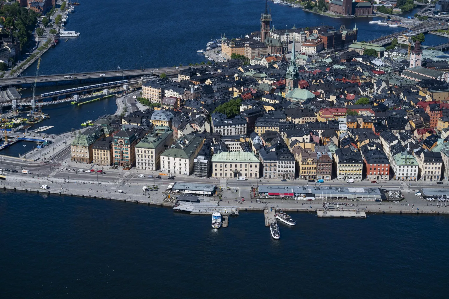 En vy över en stad med byggnader vid vattnet och båtar längs kajen.