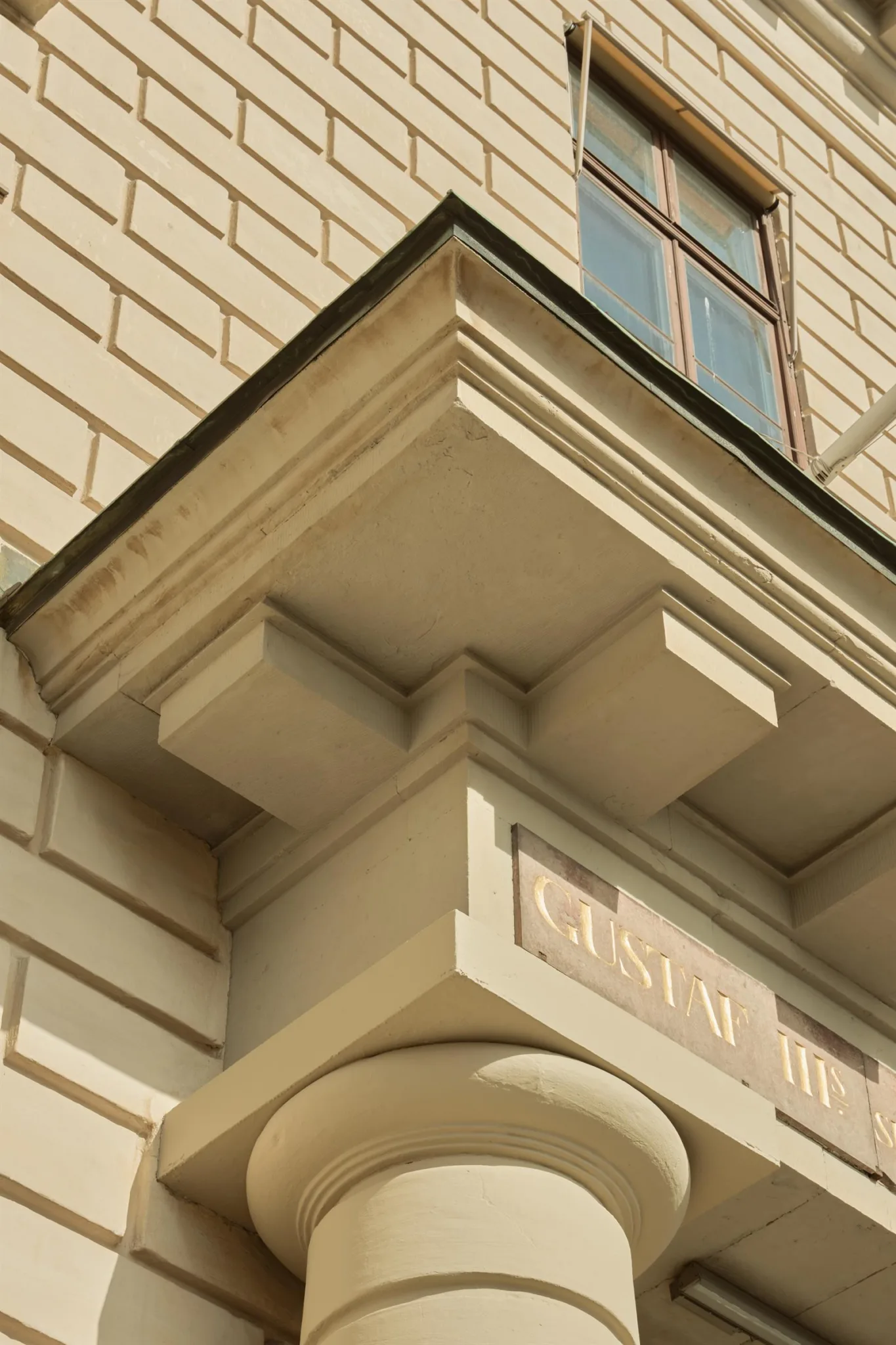 Exteriör av en byggnad med arkitektoniska detaljer och texten "Gustav III".