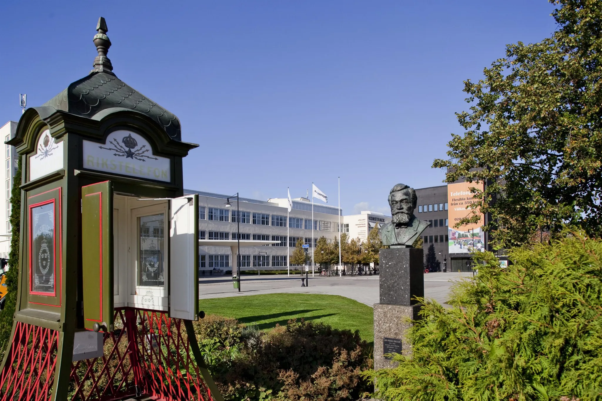 5. En staty och en liten byggnad bredvid en grönskande park med kontorsbyggnader i bakgrunden.