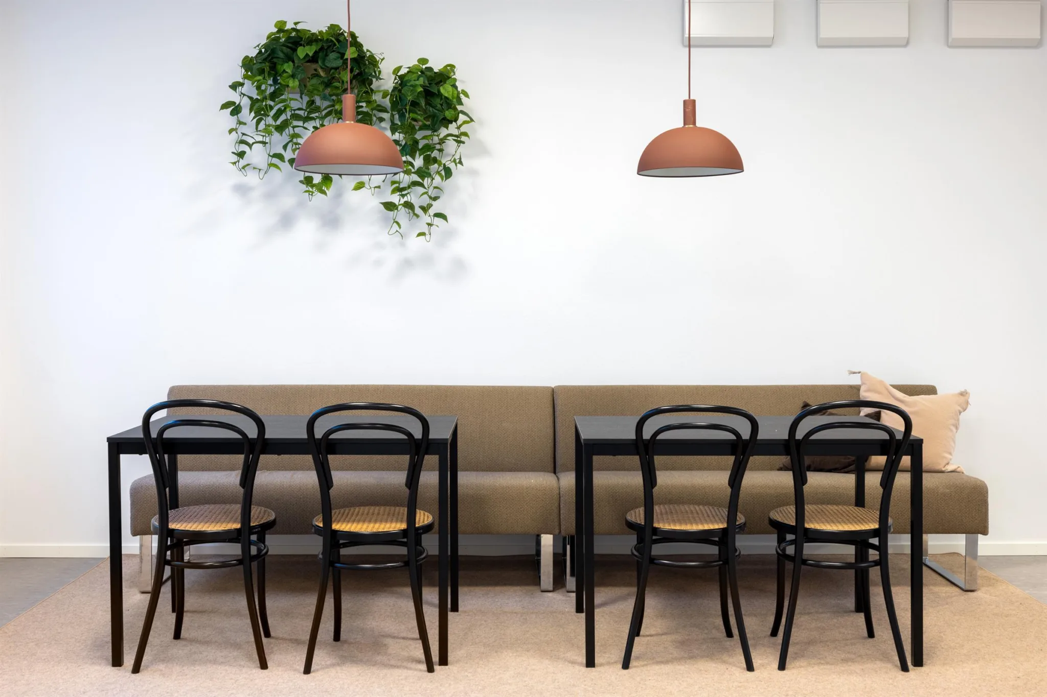 4. Matplats med två bord, svarta stolar och väggdekorationer med växter och hängande lampor.