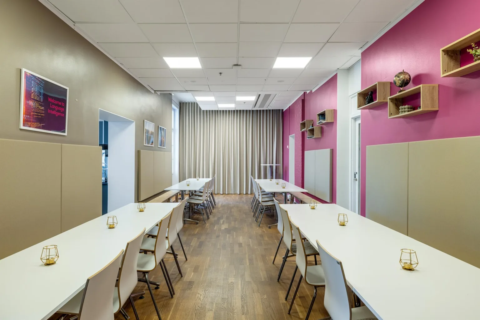 3. Ett konferensrum med flera vita bord och stolar, rosa och beige väggar samt gardiner.