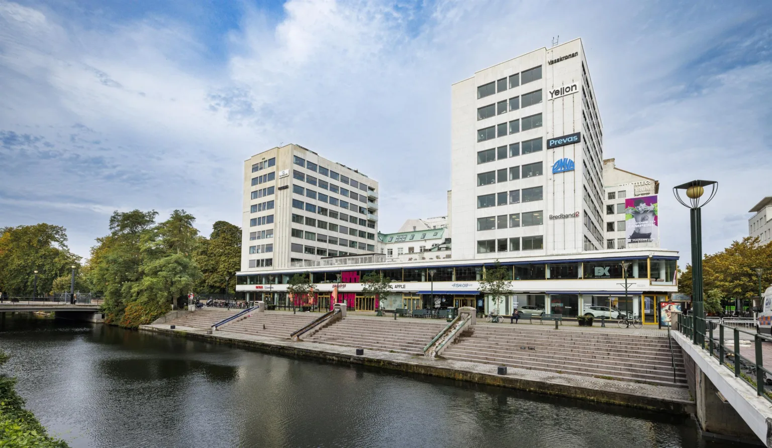 1. Två vita byggnader med flera våningar, placerade vid en kanal med trappor som leder ner mot vattnet.