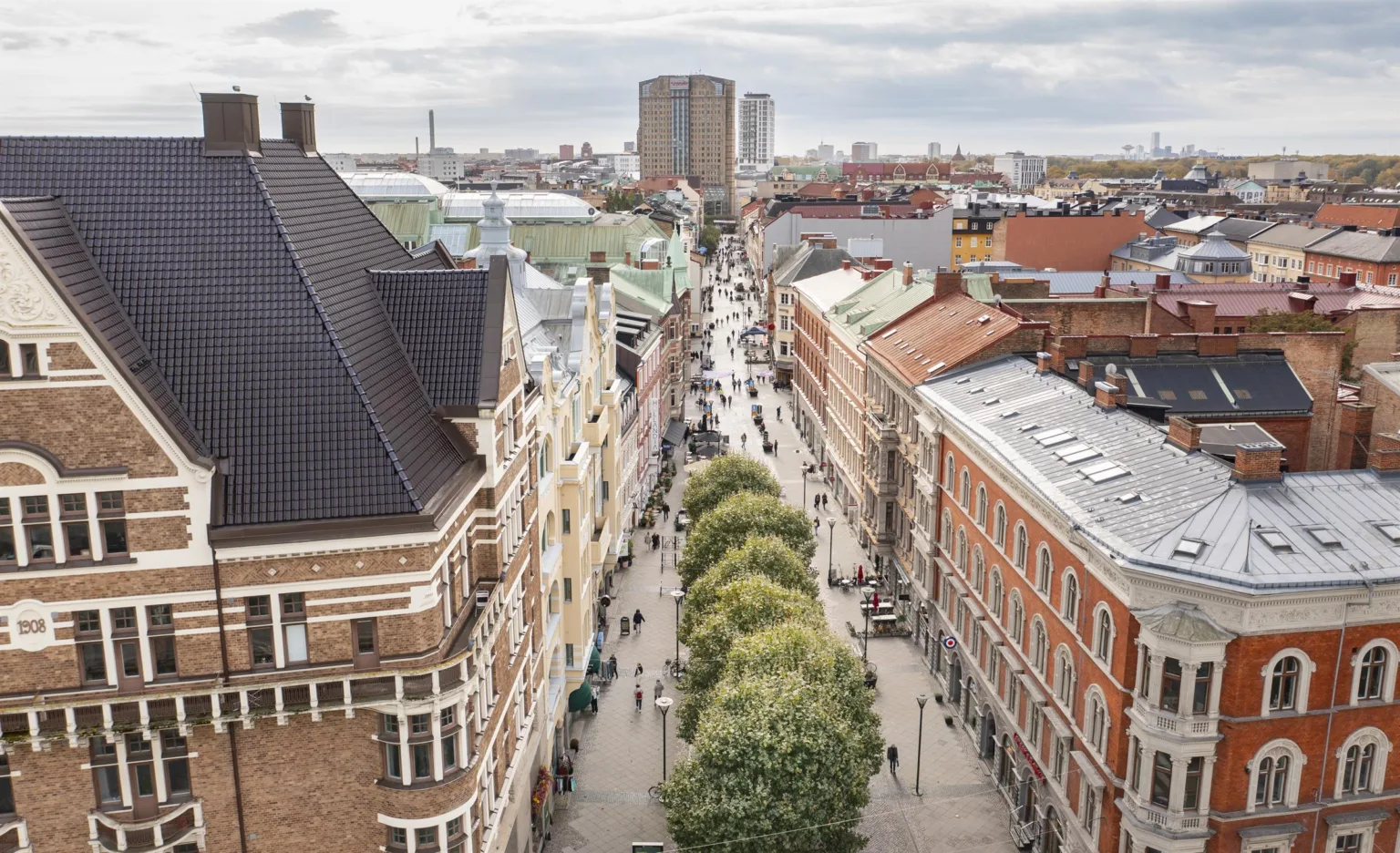 En fågelvy över en stadsgata kantad av träd och omgiven av byggnader.