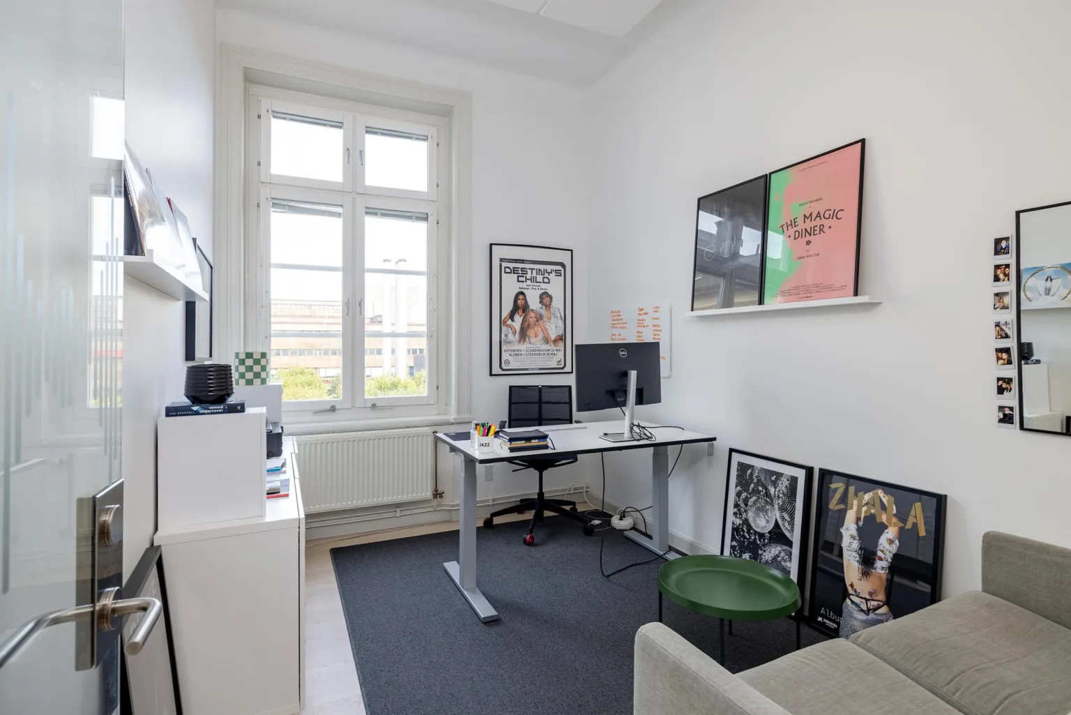 2. Ett mindre kontorsrum med skrivbord, dator, väggdekorationer och en soffa.