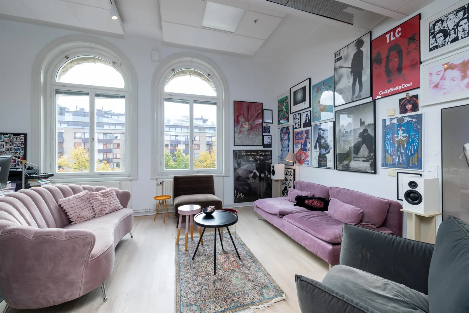 3. Ett vardagsrumsliknande utrymme med rosa soffor, bord och väggar dekorerade med tavlor och affischer.