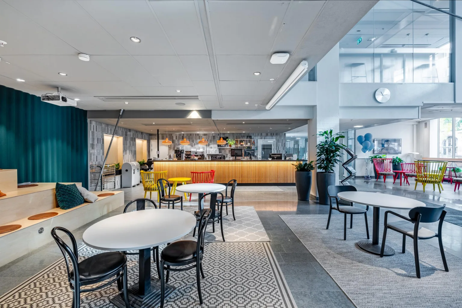 Ett modernt caféområde med bord, stolar och en upplyst disk i en ljus öppen miljö.