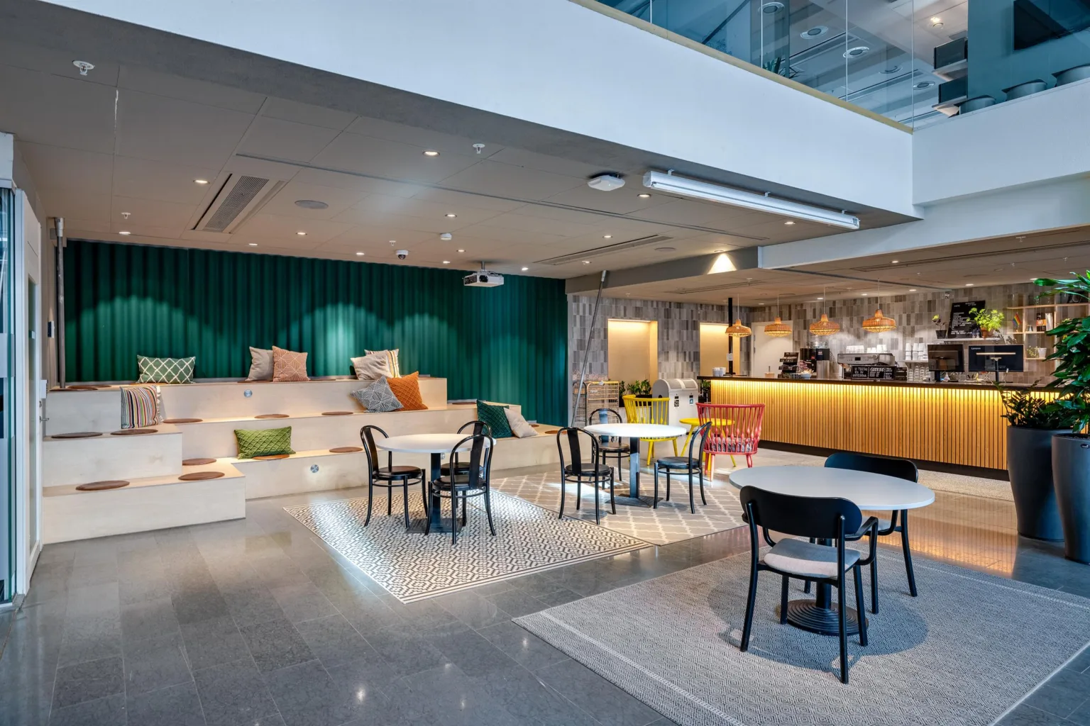 En modern lounge med sittplatser, bord och en bardisk, dekorativa kuddar och belysning.