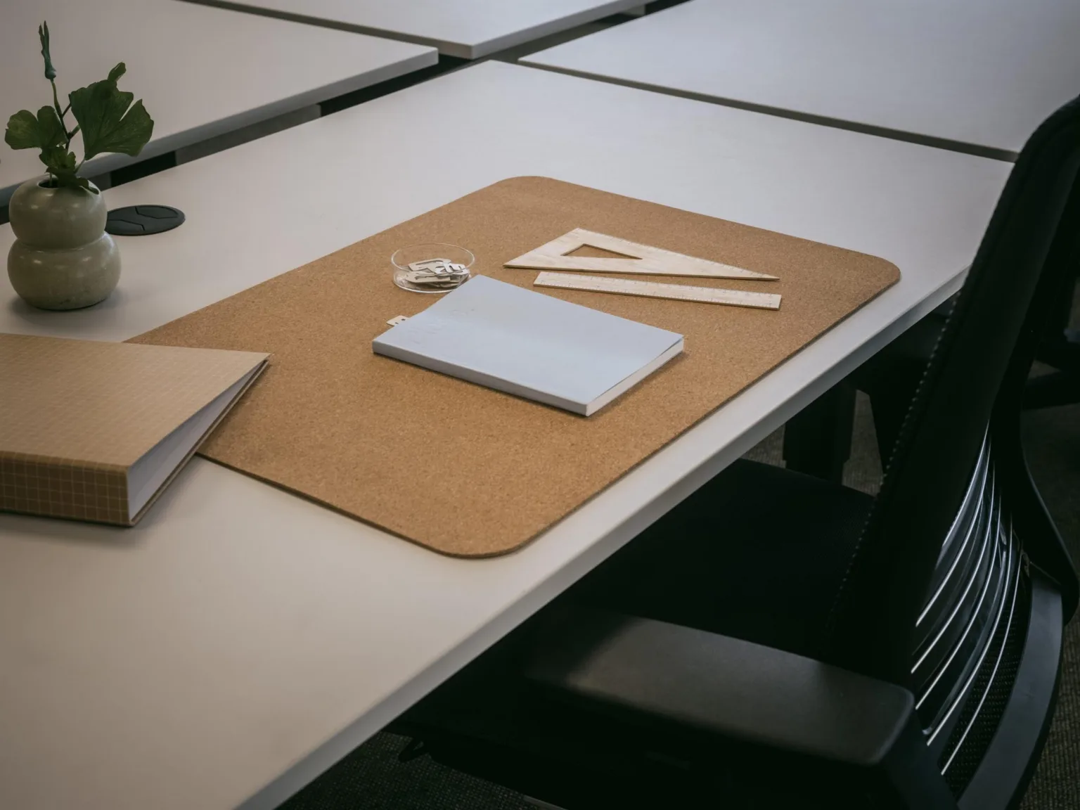 En skrivbordsmatta med en anteckningsbok, linjal och penna placerad på ett bord i ett klassrum.