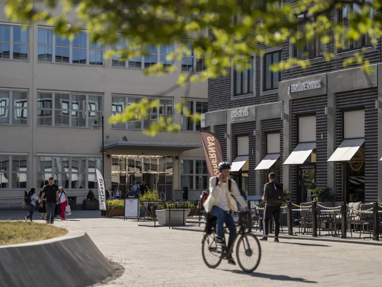 En person cyklar på en innergård omgiven av byggnader med butiksfasader.