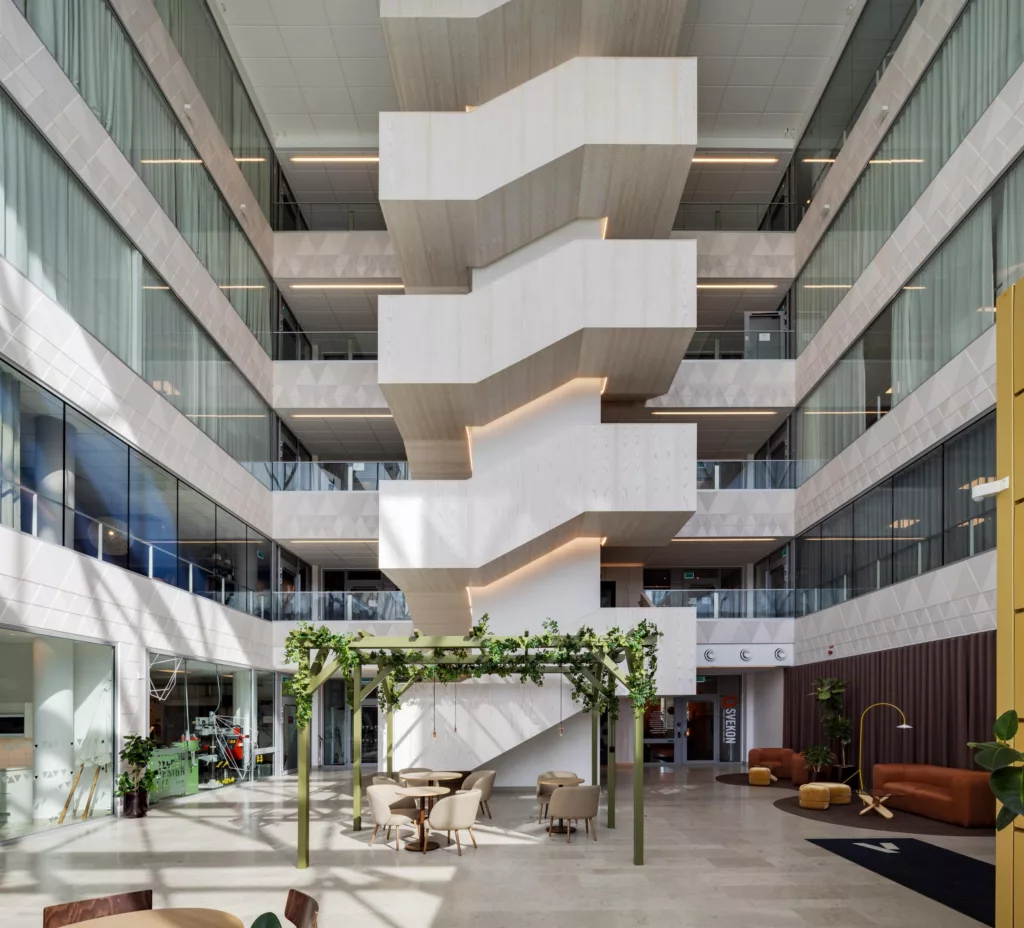 4. En inomhusmiljö med vit spiraltrappa, glasväggar och grön växtdekoration i centrum.
