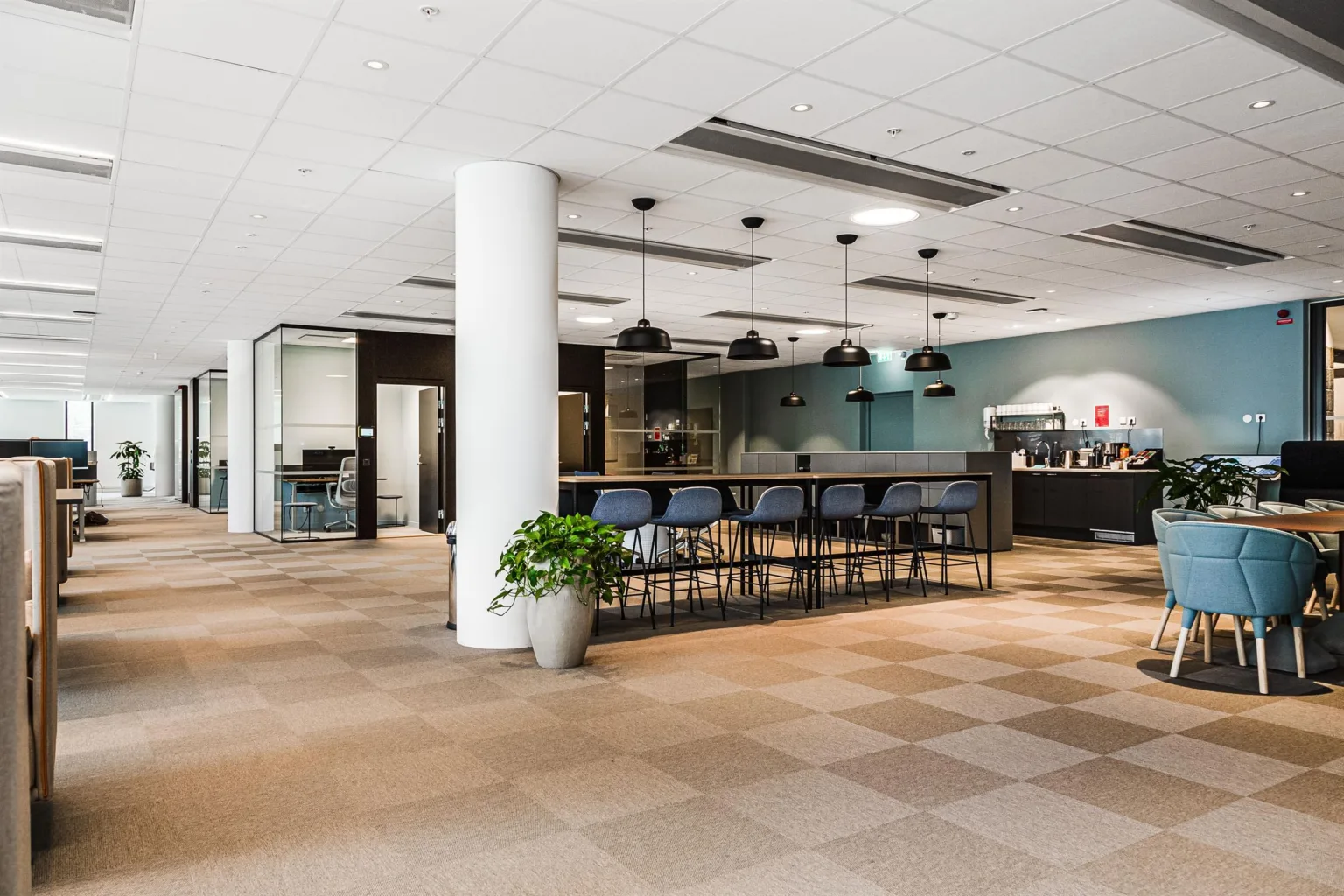 5. En ljus matplats med höga bord och stolar, växter, köksutrustning och modern inredning.