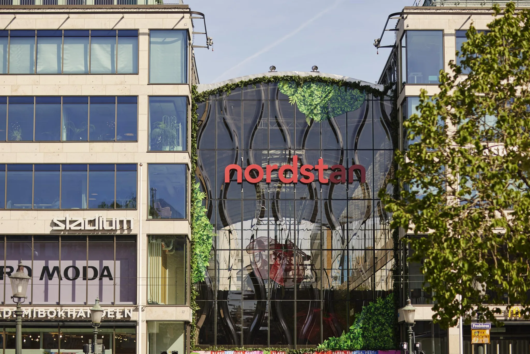 Fasaden av Nordstan köpcentrum med glas och grönskande växtdetaljer samt röd texten "nordstan".
