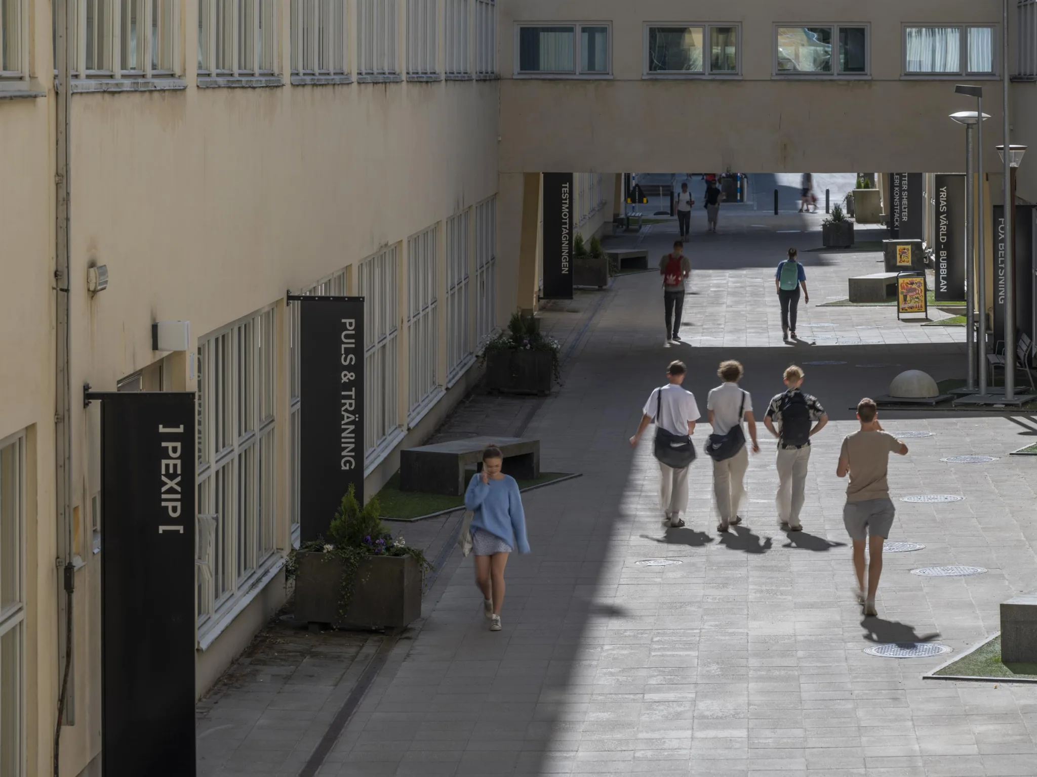 En gångväg mellan byggnader, med människor som går och en skylt märkt "1 våning".