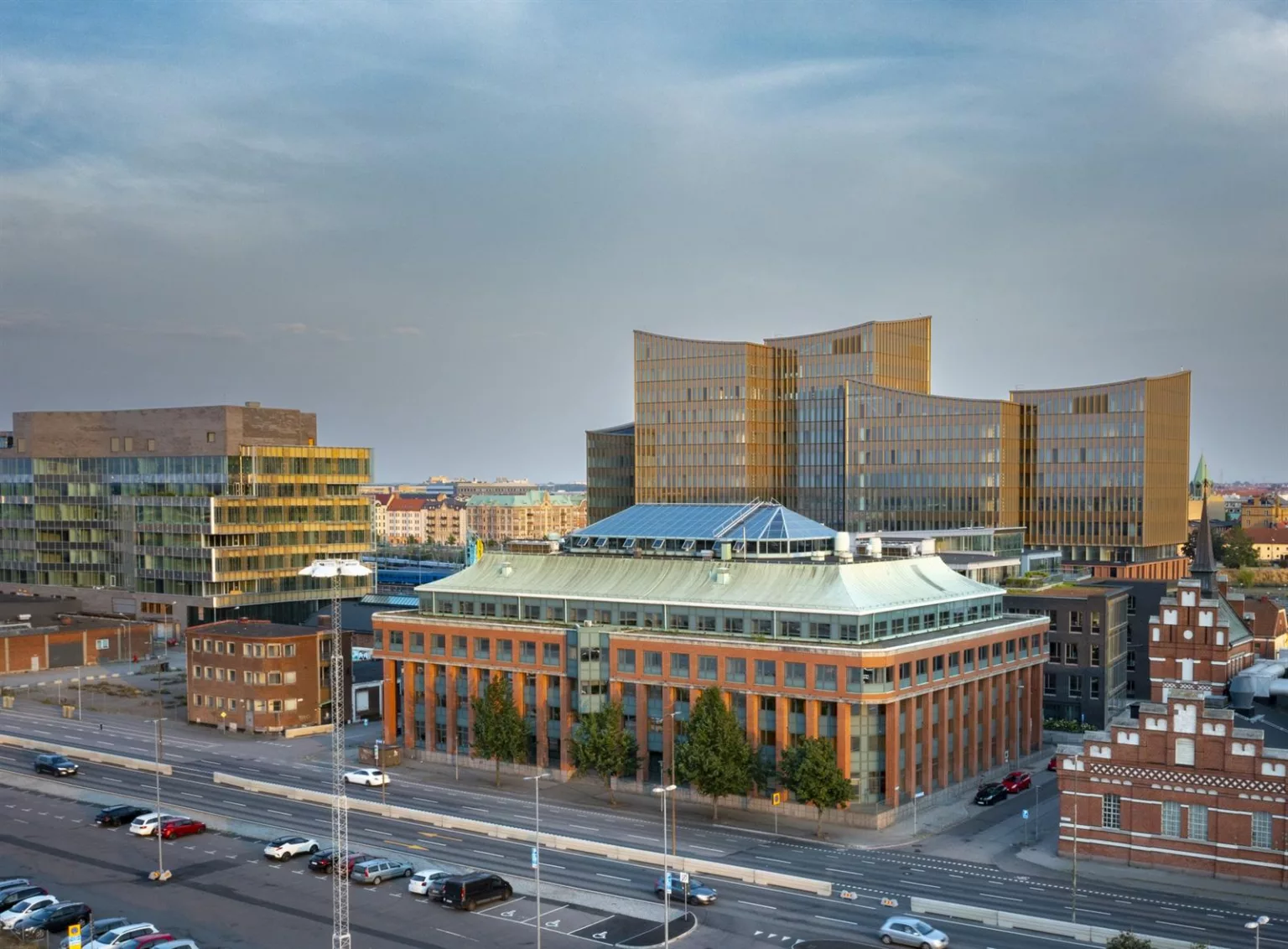2. Utsikt över ett område med moderna byggnader, inklusive en äldre byggnad med grönt tak i förgrunden.