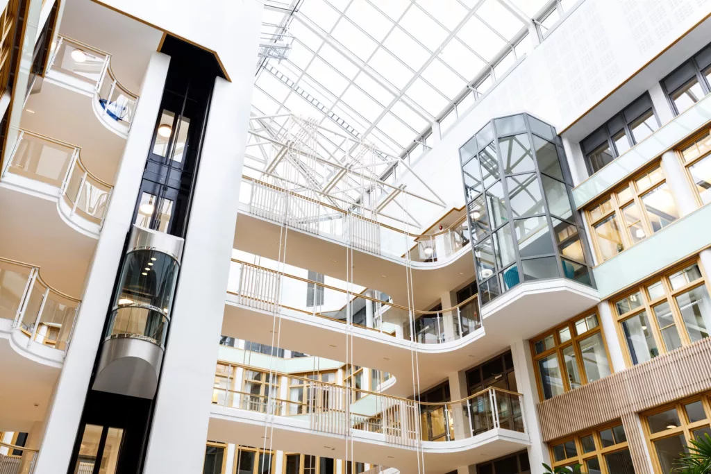 1. Interiör av en modern byggnad med flera våningsplan och glasväggar under ett ljust glastak.