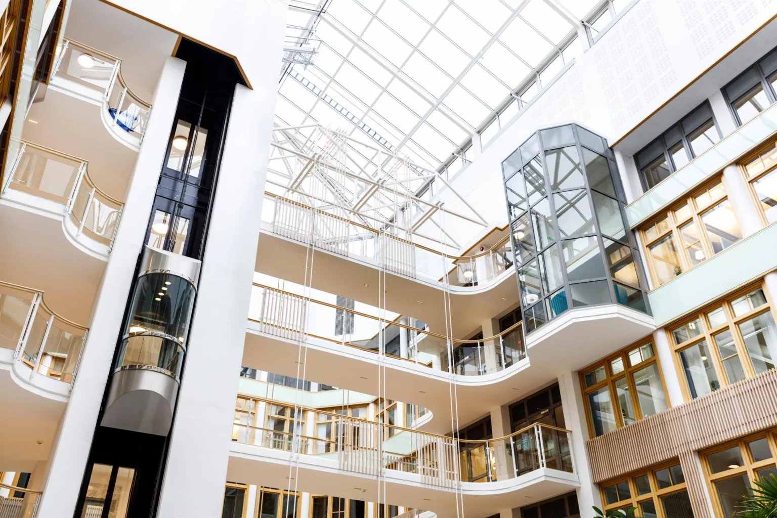1. Interiör av en modern byggnad med flera våningsplan och glasväggar under ett ljust glastak.